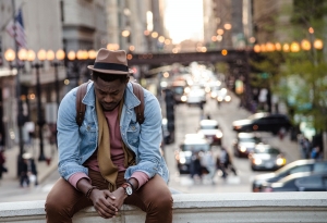 A young man alone sitting above a croweded street