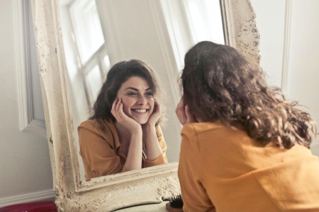 A Woman Staring Happily at Her Mirror Image